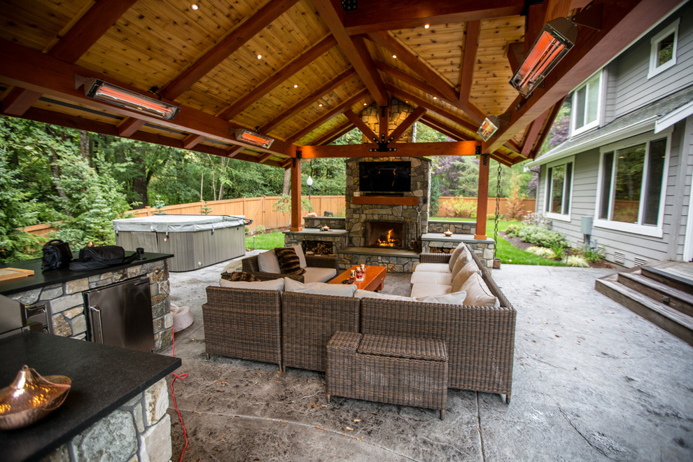 Exemple d'une grande terrasse arrière craftsman avec une cuisine d'été, une dalle de béton et une extension de toiture.