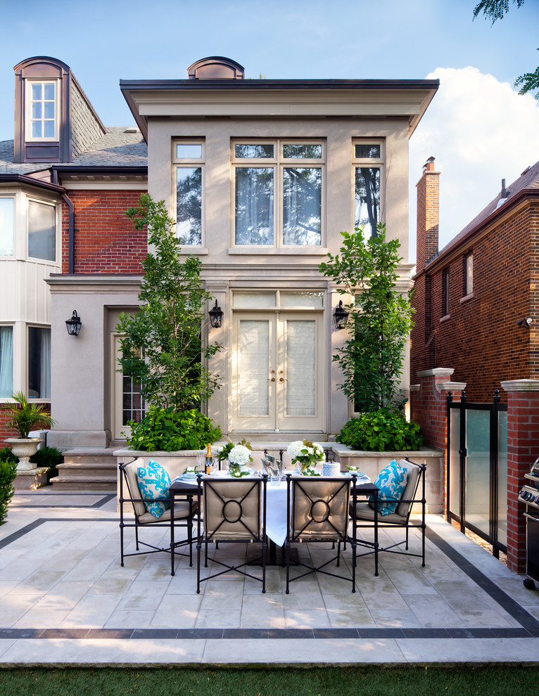 Foto di un grande patio o portico tradizionale dietro casa con un giardino in vaso, pavimentazioni in pietra naturale e nessuna copertura