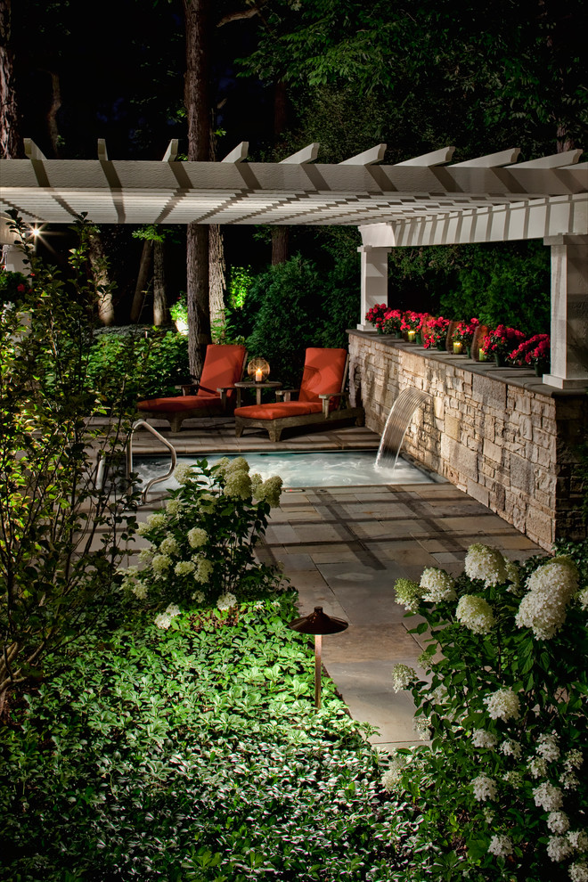Example of a large classic backyard stone patio fountain design in Chicago with a pergola