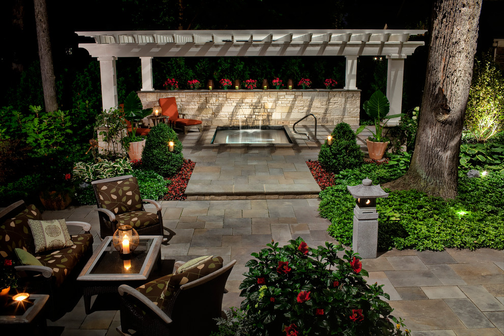 Foto di un grande patio o portico tradizionale dietro casa con un gazebo o capanno e pavimentazioni in pietra naturale