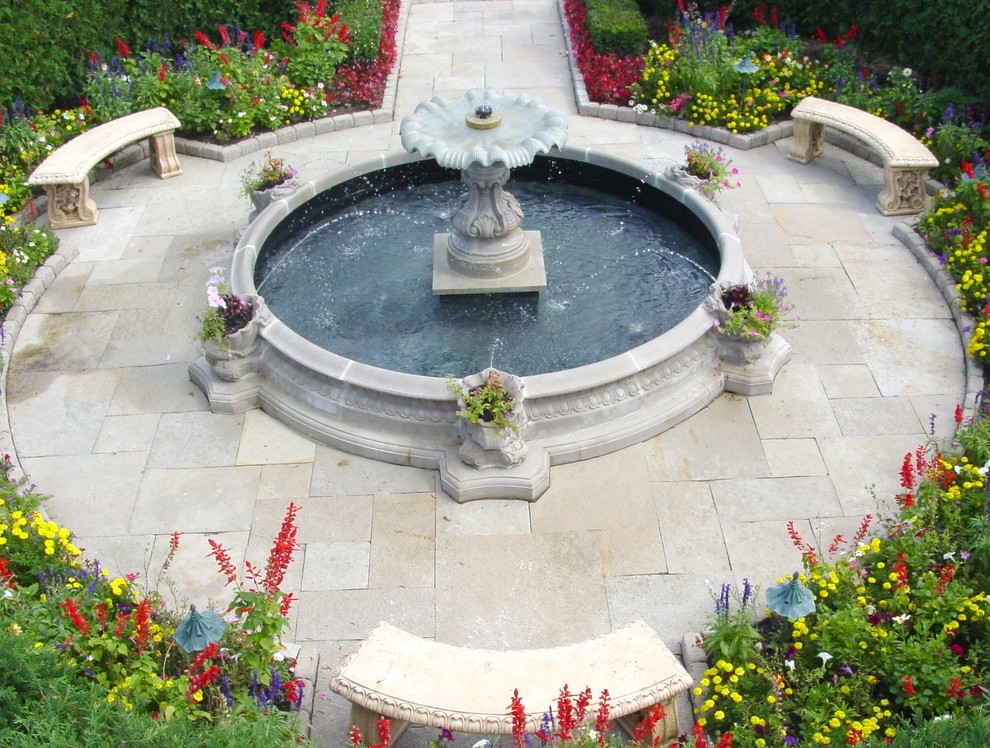 На фото: огромный двор на переднем дворе в классическом стиле с фонтаном и покрытием из каменной брусчатки с