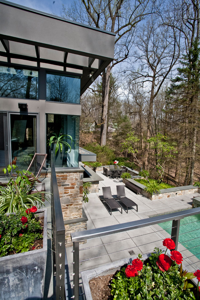 Immagine di un ampio patio o portico design dietro casa con pavimentazioni in cemento e un tetto a sbalzo