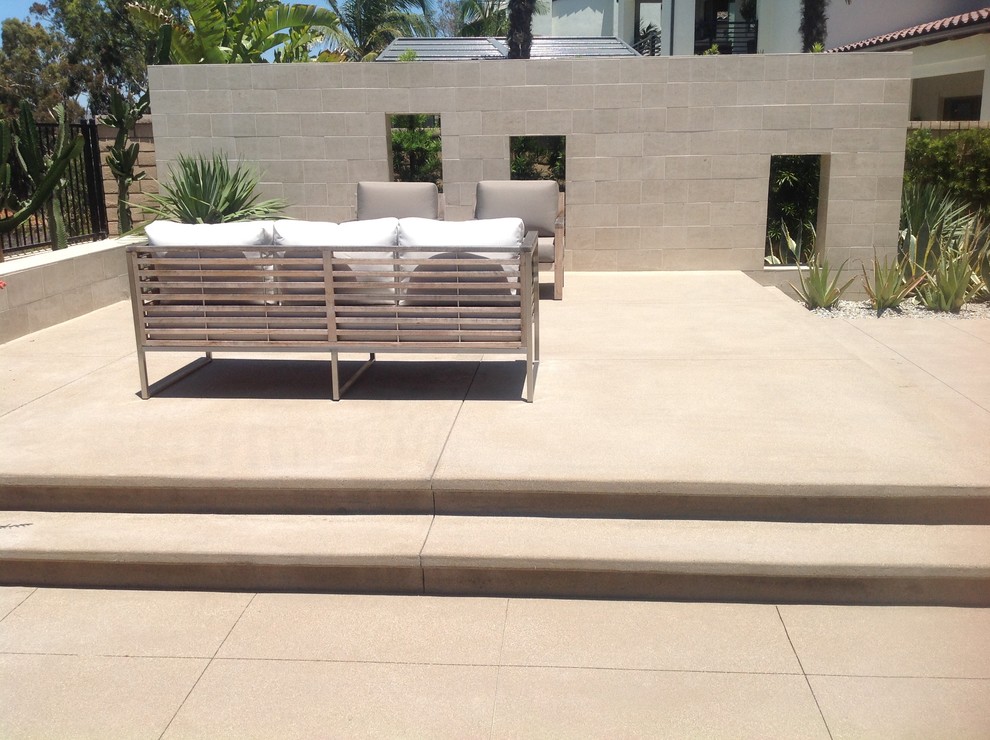Immagine di un patio o portico minimalista di medie dimensioni e dietro casa con cemento stampato, nessuna copertura e un focolare