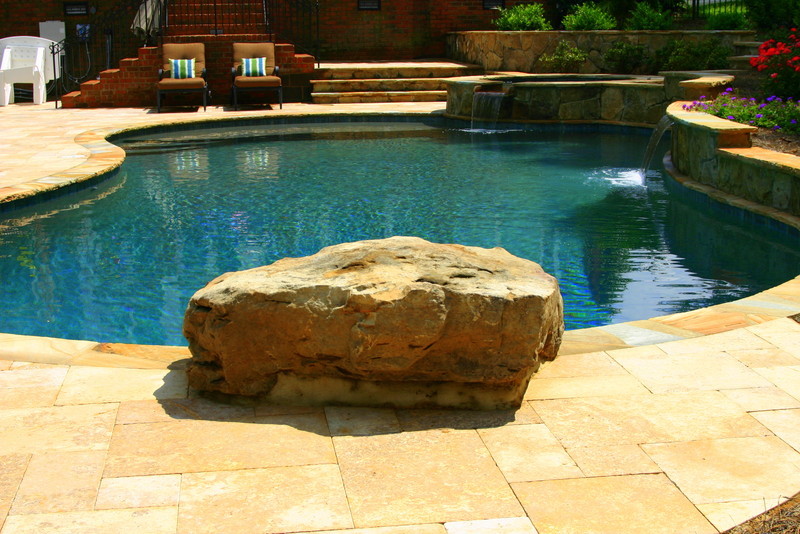 Design ideas for a medium sized mediterranean back swimming pool in Charlotte with a water feature and natural stone paving.