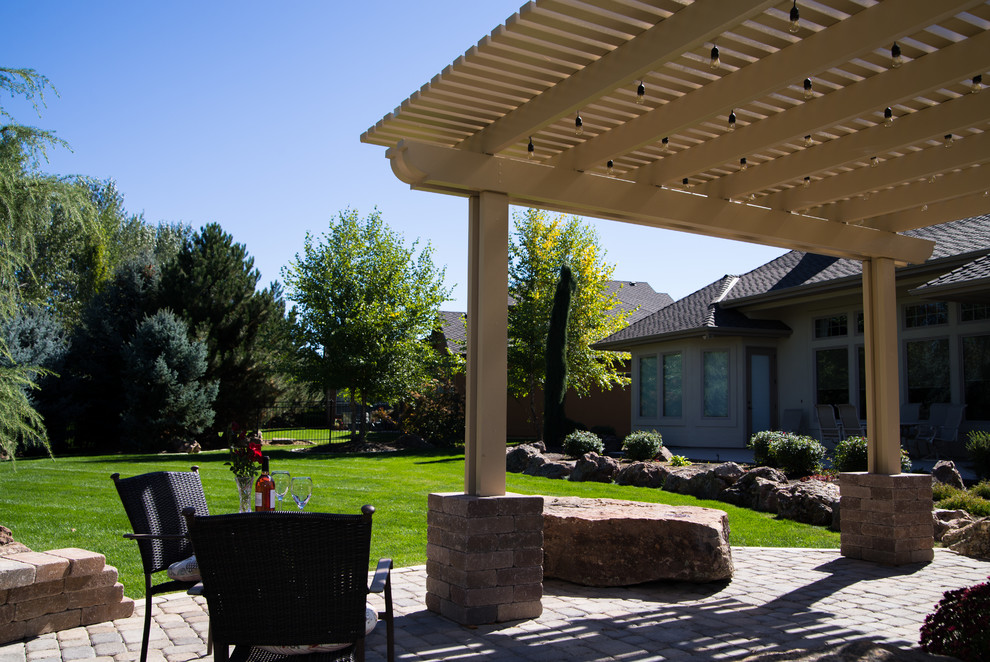Aménagement d'une terrasse arrière rétro avec une cuisine d'été, des pavés en pierre naturelle et une pergola.