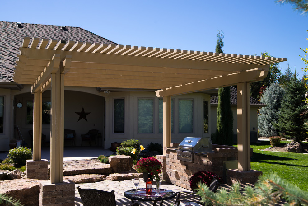 Retro Pergola hinter dem Haus mit Outdoor-Küche und Natursteinplatten in Boise