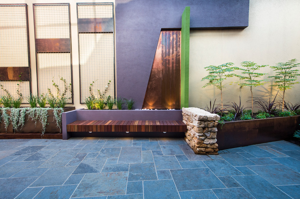 Cette image montre une terrasse design avec une cour et des pavés en pierre naturelle.