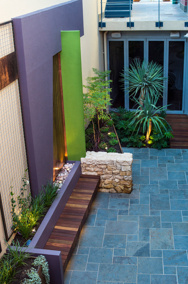 Diseño de patio actual pequeño en patio con fuente y adoquines de piedra natural