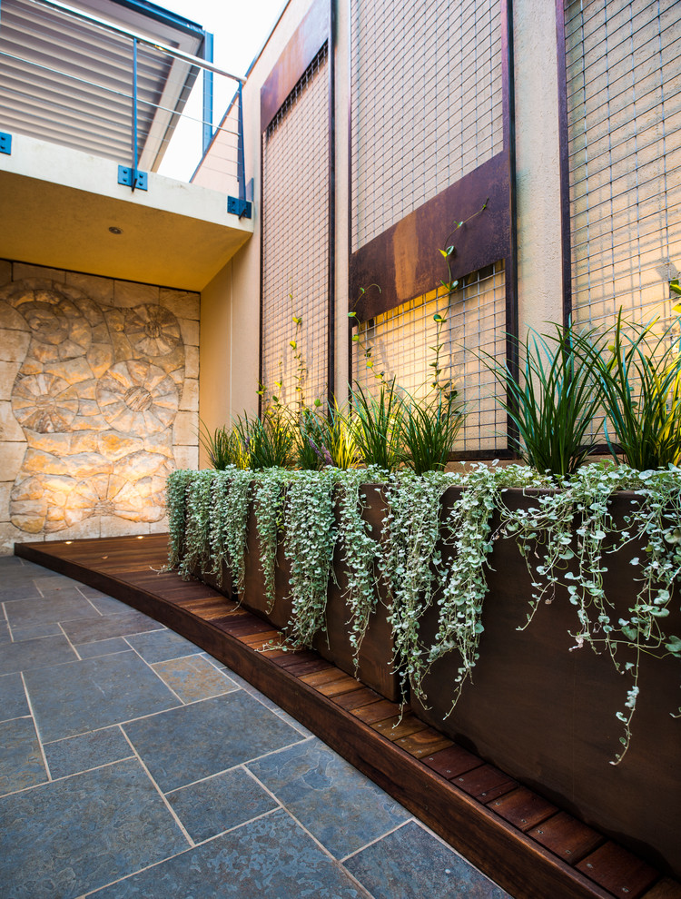 Idee per un piccolo patio o portico design in cortile con un giardino in vaso e pavimentazioni in pietra naturale