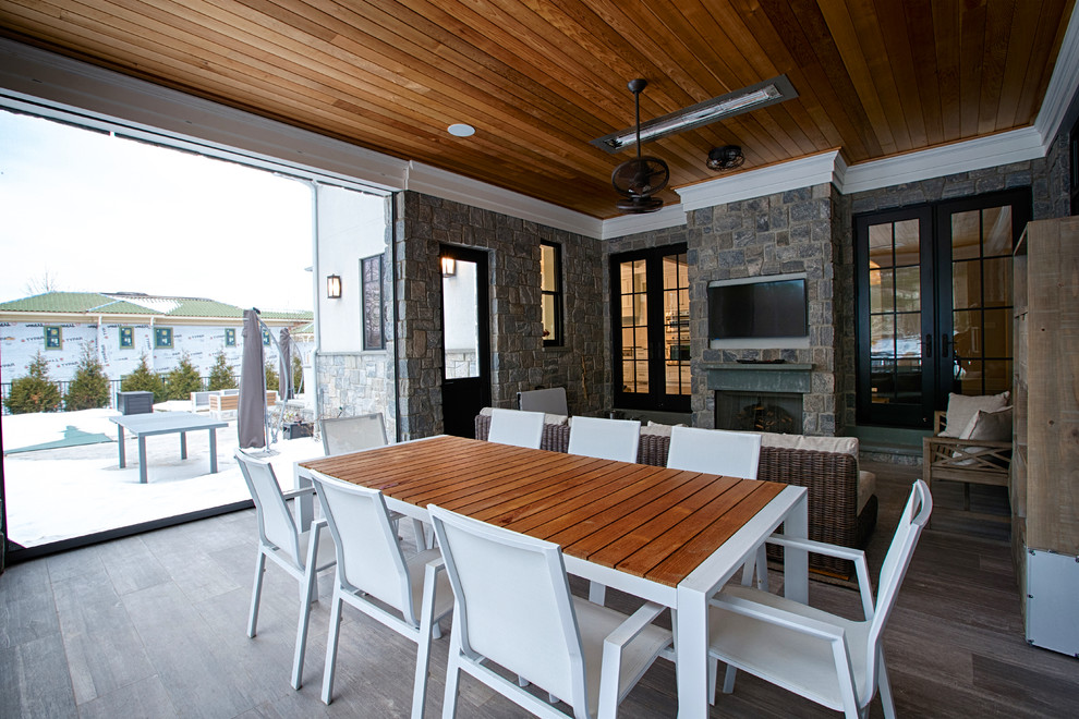 Idée de décoration pour une grande terrasse arrière tradition avec un foyer extérieur et une extension de toiture.