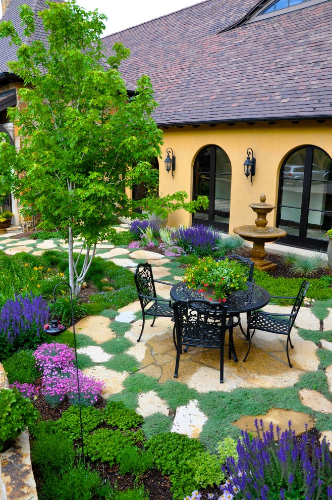 Example of a french country courtyard patio design in Denver with no cover