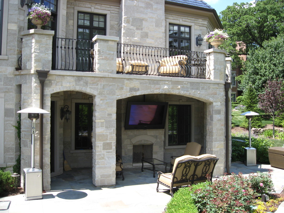 Esempio di un grande patio o portico chic dietro casa con un focolare, pavimentazioni in pietra naturale e un tetto a sbalzo