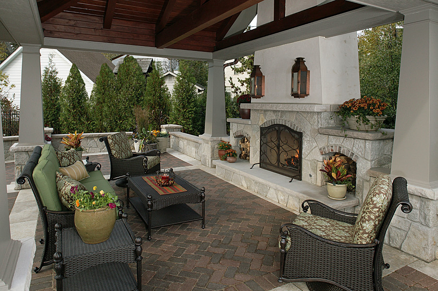 Foto di un patio o portico dietro casa e di medie dimensioni con pavimentazioni in mattoni e un focolare