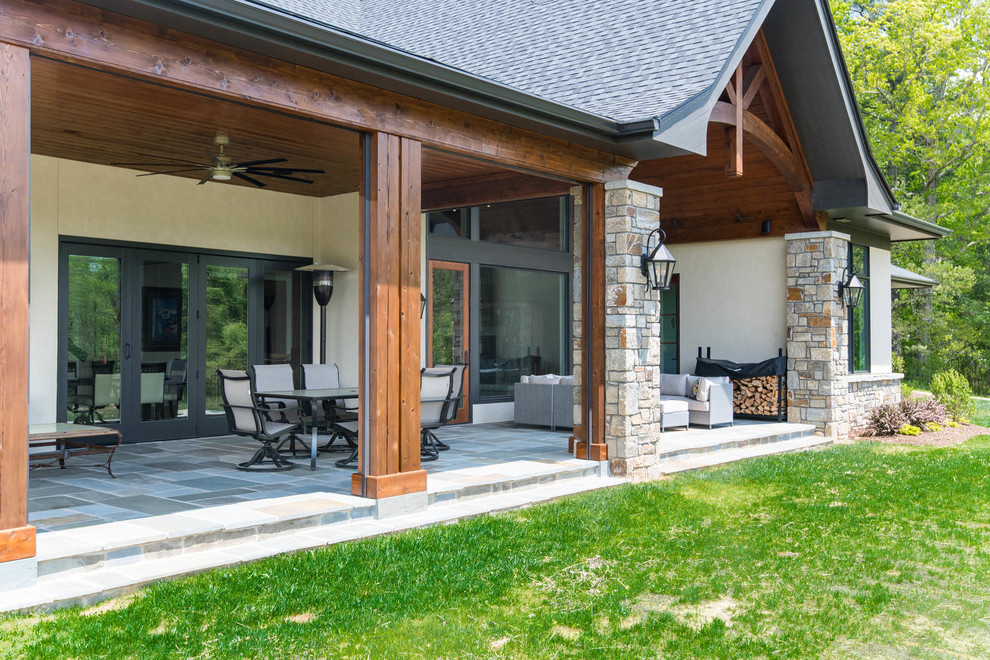 Esempio di un grande patio o portico classico dietro casa con pavimentazioni in pietra naturale e un tetto a sbalzo