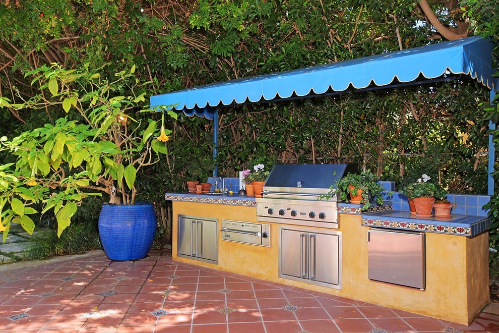 Aménagement d'une terrasse méditerranéenne avec une cuisine d'été et du carrelage.