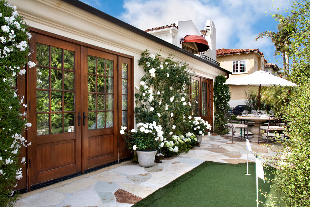 Mediterranean patio in Orange County with natural stone paving and no cover.