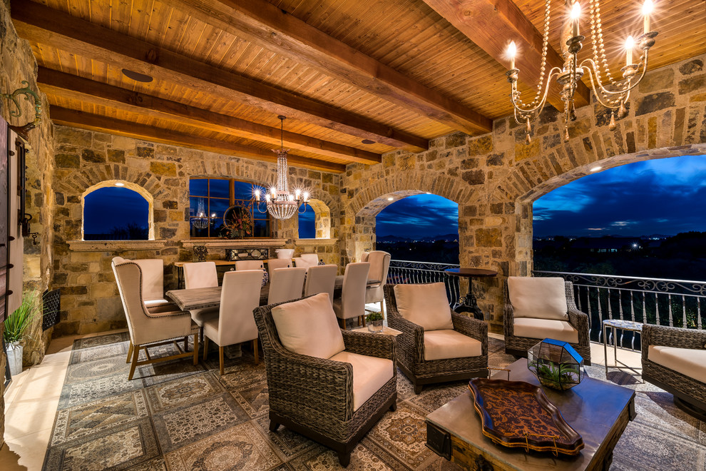 Expansive rustic back patio in Phoenix with a fire feature, natural stone paving and a roof extension.