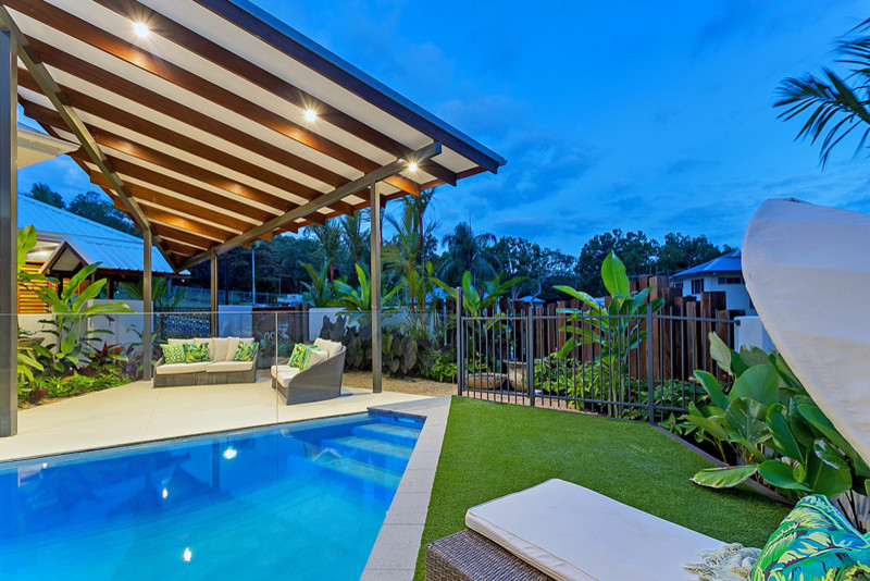 Modelo de patio tropical grande en patio trasero con suelo de baldosas y cenador