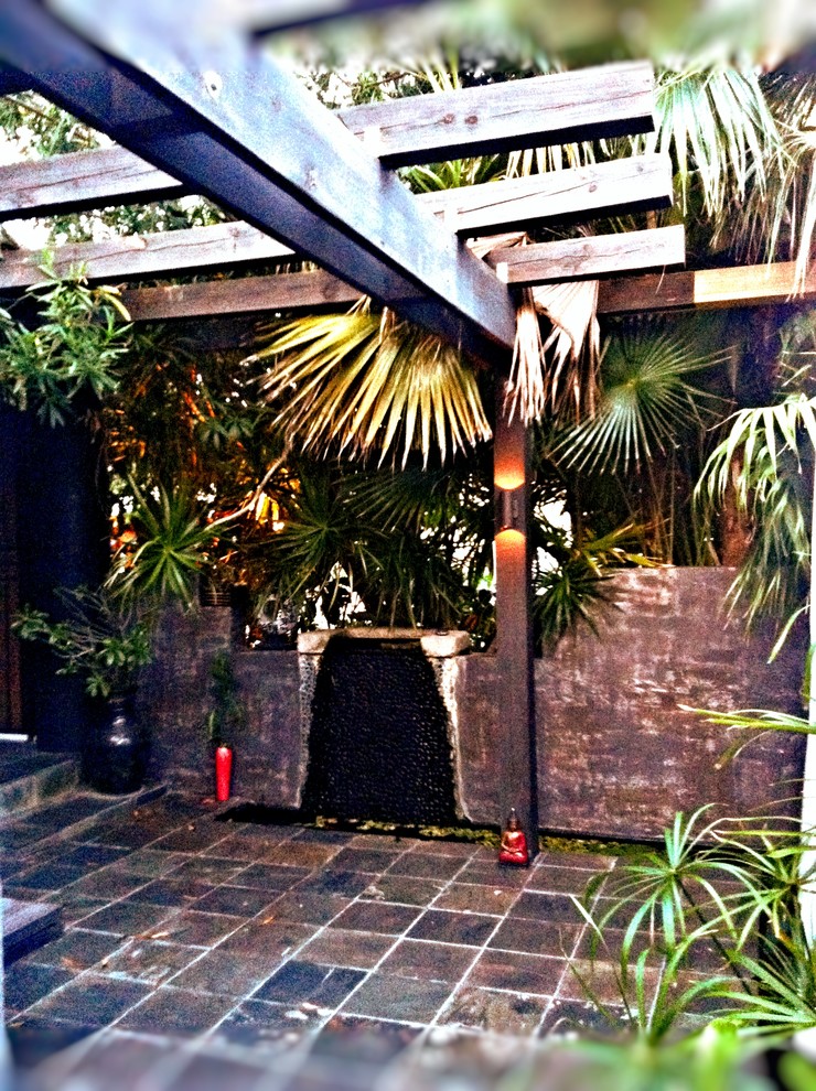 Diseño de patio asiático pequeño en patio delantero con fuente, pérgola y suelo de baldosas