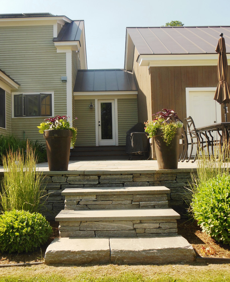 Esempio di un patio o portico chic di medie dimensioni e dietro casa con pavimentazioni in pietra naturale e un tetto a sbalzo