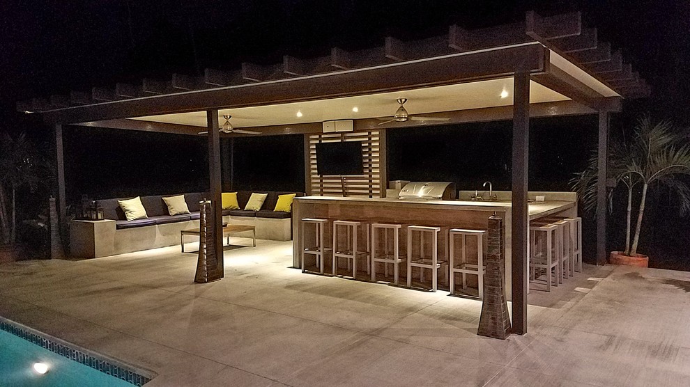 Exemple d'une grande terrasse arrière chic avec une cuisine d'été, une dalle de béton et une pergola.