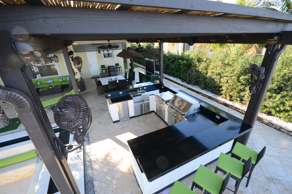 Example of a huge trendy backyard stone patio kitchen design in Miami with a pergola