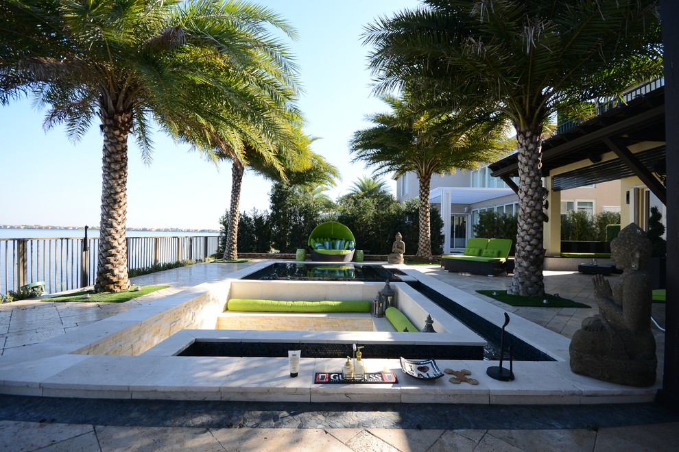 Photo of an expansive contemporary back patio in Miami with an outdoor kitchen, natural stone paving and a pergola.