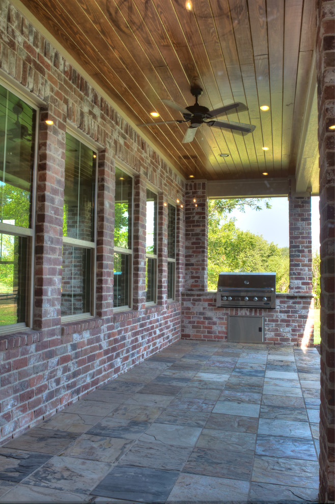 На фото: двор на заднем дворе в классическом стиле с летней кухней, покрытием из каменной брусчатки и навесом с