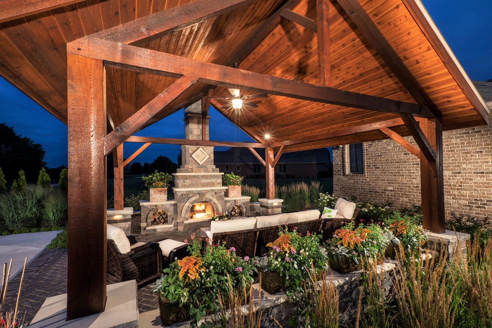 Photo of a large contemporary back patio in Chicago with a fireplace, brick paving and a gazebo.