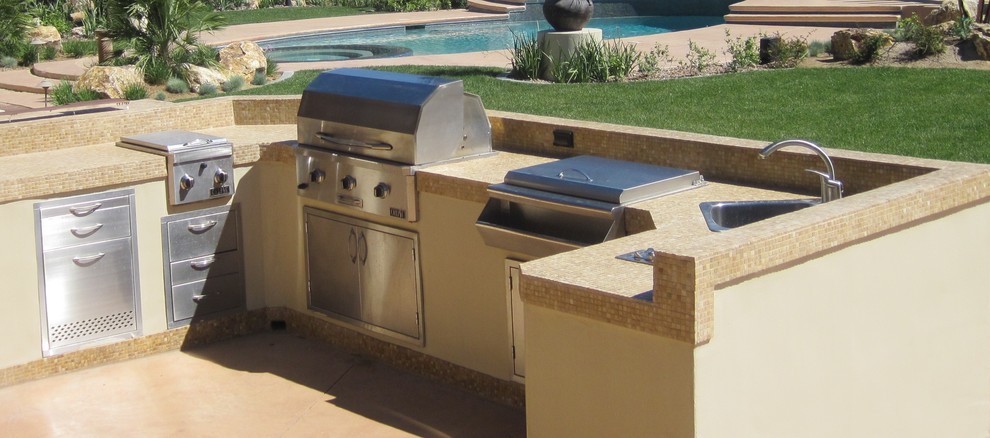 Exemple d'une très grande terrasse arrière moderne avec une cuisine d'été, des pavés en pierre naturelle et une pergola.