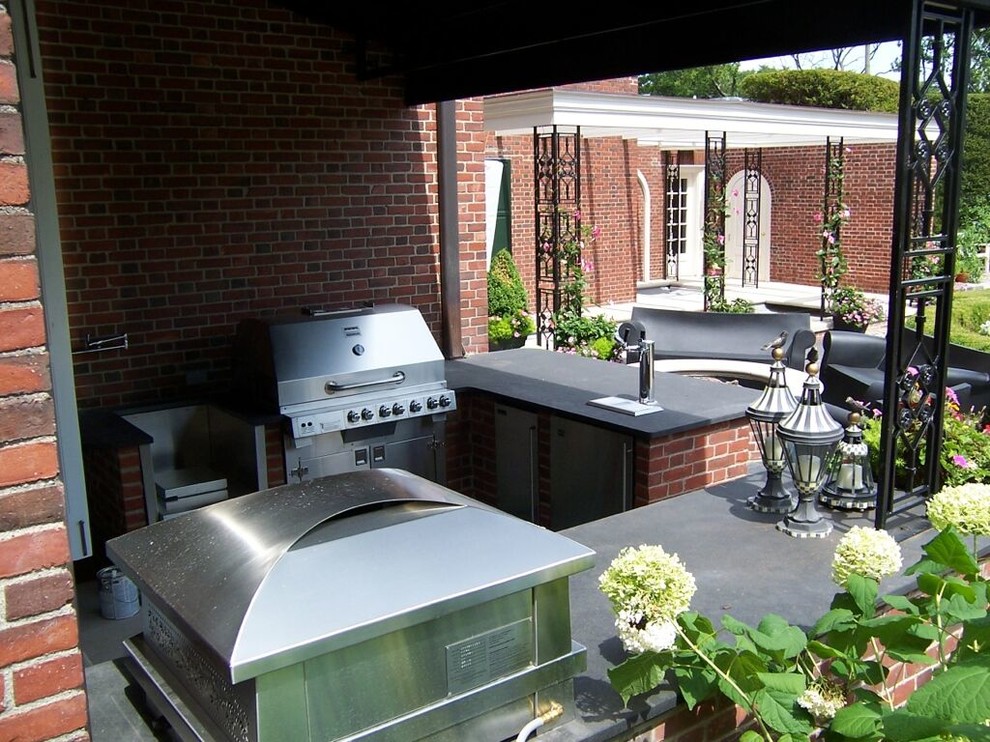 Modelo de patio tradicional grande sin cubierta en patio trasero con cocina exterior y adoquines de ladrillo