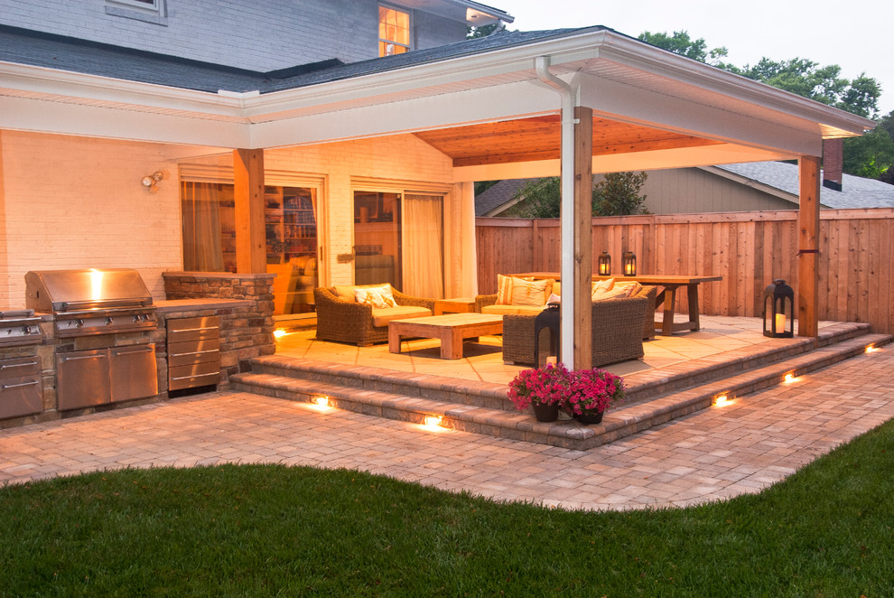 Exemple d'une grande terrasse arrière chic avec une cuisine d'été, des pavés en brique et une extension de toiture.