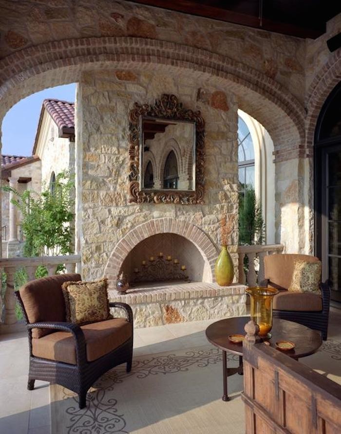 Foto di un grande patio o portico mediterraneo dietro casa con un focolare, pavimentazioni in pietra naturale e un tetto a sbalzo