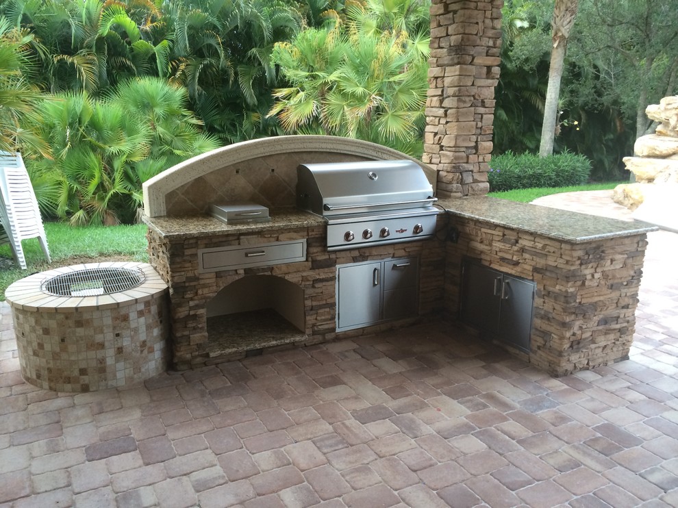 Patio kitchen - large tropical backyard stone patio kitchen idea in Miami with a gazebo