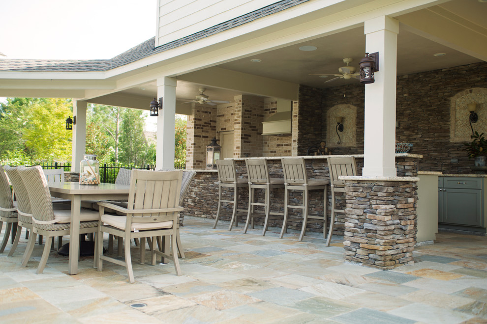 Idee per un grande patio o portico tradizionale dietro casa con pavimentazioni in pietra naturale e un tetto a sbalzo