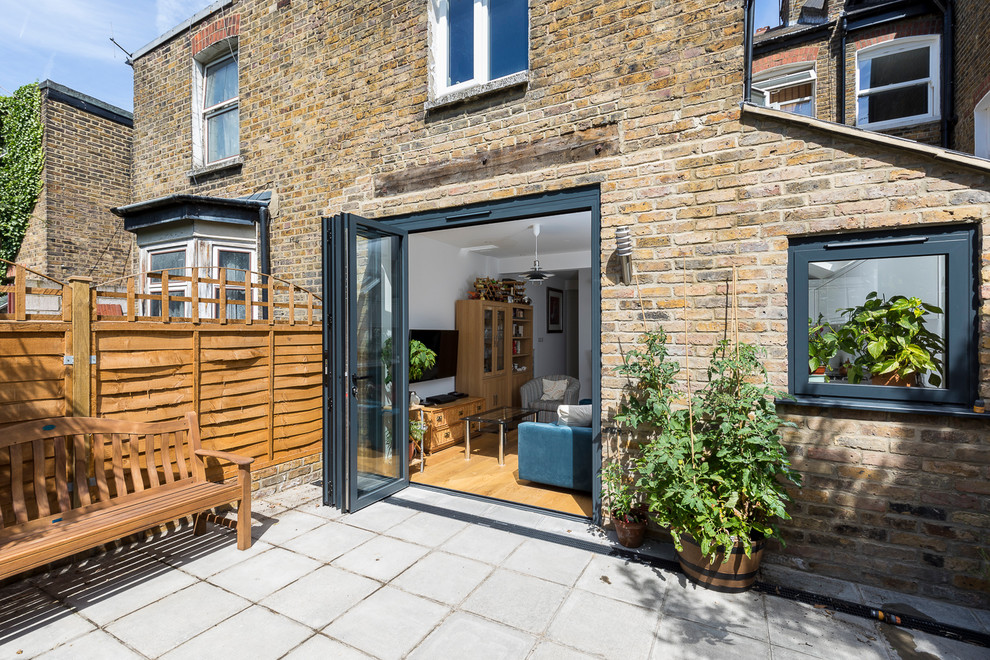 Patio - mid-sized traditional backyard concrete paver patio idea in London