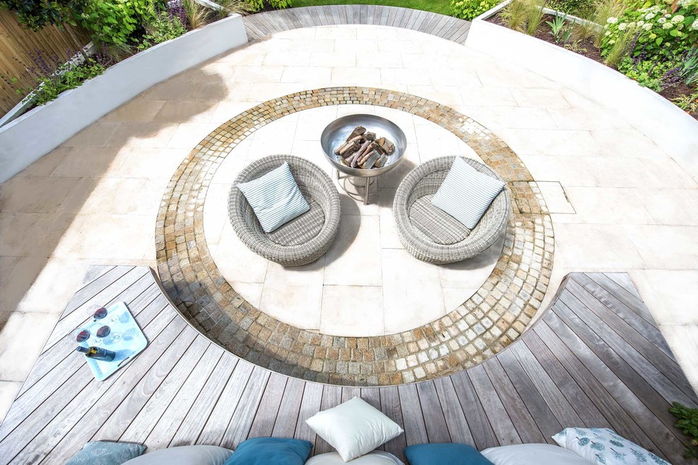 Idée de décoration pour une terrasse arrière design avec un foyer extérieur et des pavés en pierre naturelle.