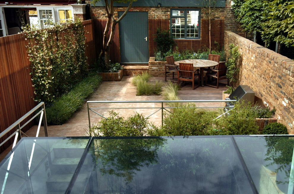 Inspiration for a contemporary back patio in London with natural stone paving.