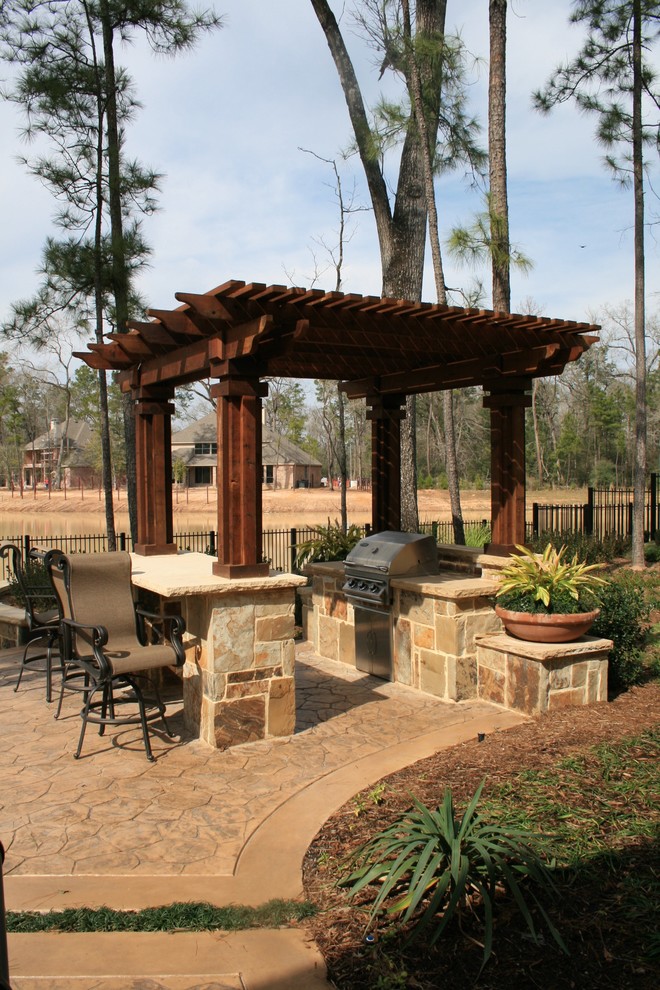 Design ideas for a medium sized traditional back patio in Dallas with an outdoor kitchen, stamped concrete and a pergola.