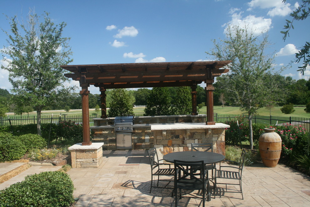 Mid-sized elegant backyard stamped concrete patio kitchen photo in Dallas with a pergola