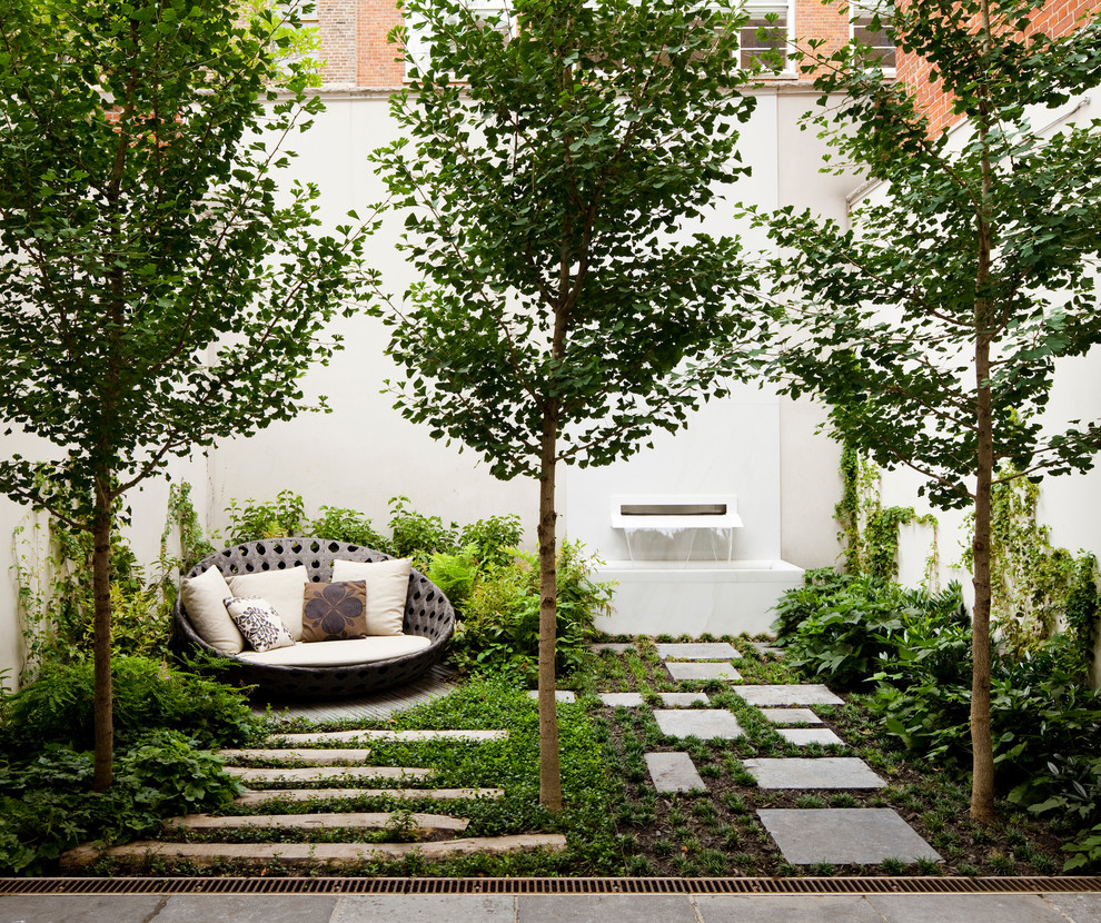 Diseño de patio clásico renovado de tamaño medio sin cubierta en patio trasero con fuente y adoquines de piedra natural