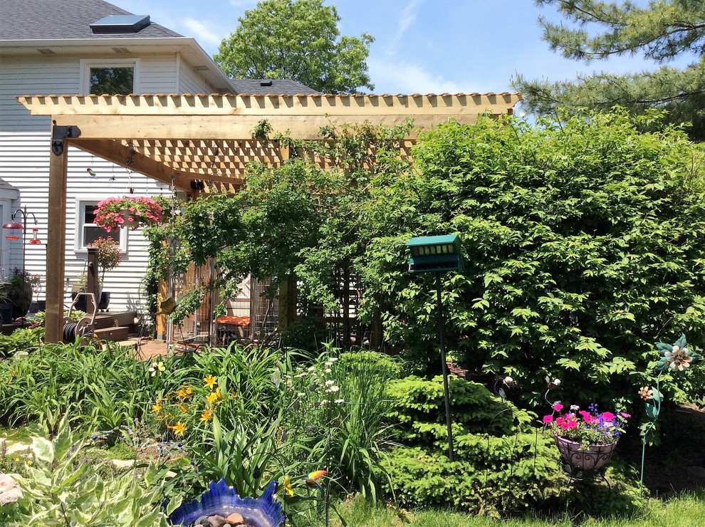 Ispirazione per un patio o portico stile americano di medie dimensioni e dietro casa con pavimentazioni in pietra naturale e una pergola