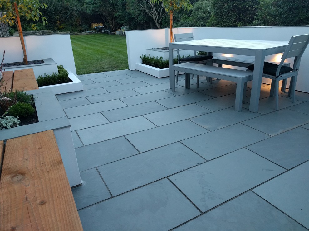 Medium sized contemporary side patio in Other with natural stone paving.