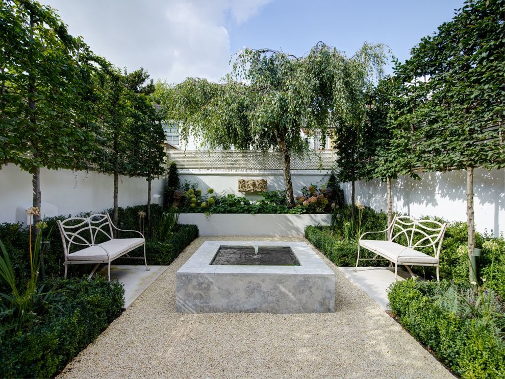 This is an example of a small contemporary back patio in London with a water feature, gravel and no cover.