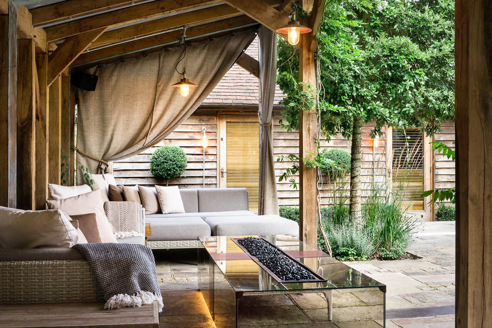 Cette photo montre une grande terrasse tendance avec une cour, des pavés en pierre naturelle et un foyer extérieur.