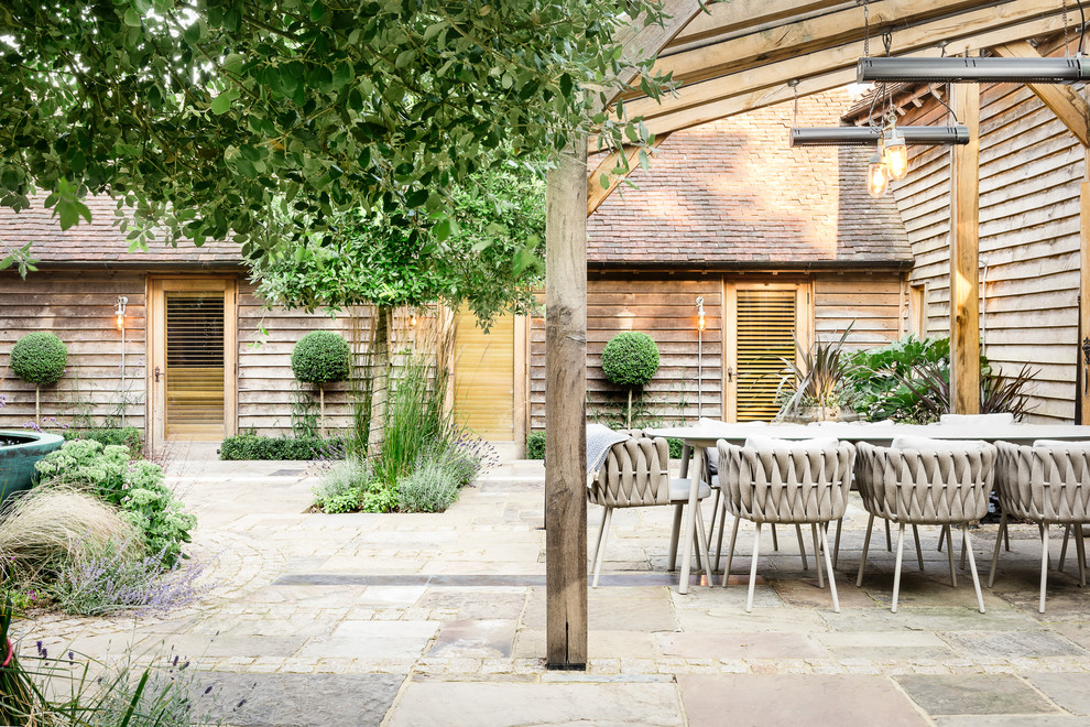 Immagine di un grande patio o portico design in cortile con pavimentazioni in pietra naturale