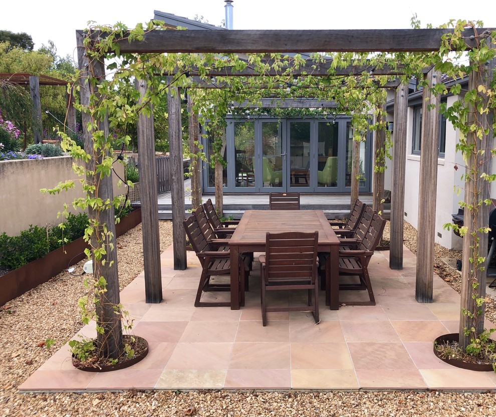 Photo of a small contemporary courtyard patio in Other with tiled flooring and a pergola.