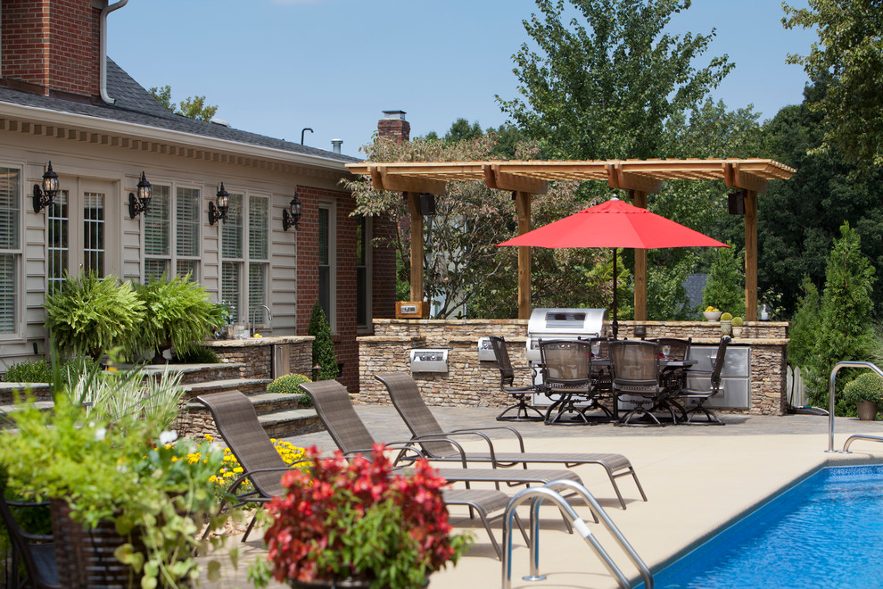 Inspiration for a mid-sized timeless backyard stone patio kitchen remodel in Charlotte with a pergola