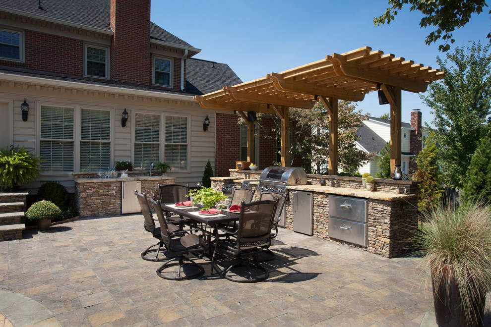 Exemple d'une terrasse arrière chic de taille moyenne avec une cuisine d'été et des pavés en pierre naturelle.