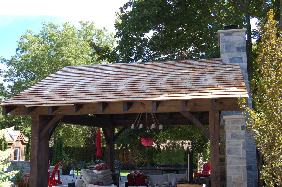 Cette image montre une terrasse arrière chalet de taille moyenne avec un foyer extérieur, des pavés en brique et une extension de toiture.